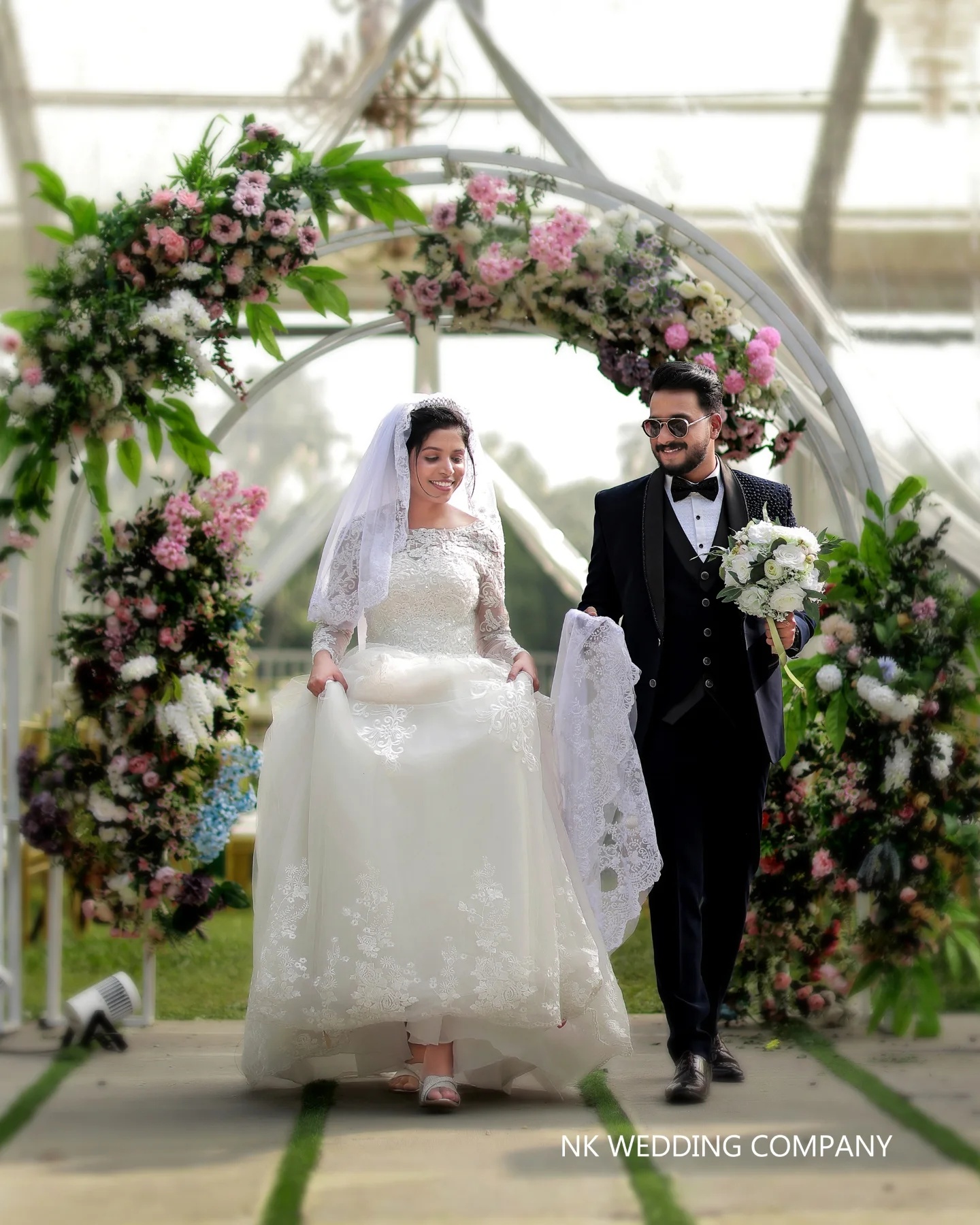 Newlyweds walking beneath a floral wedding arch