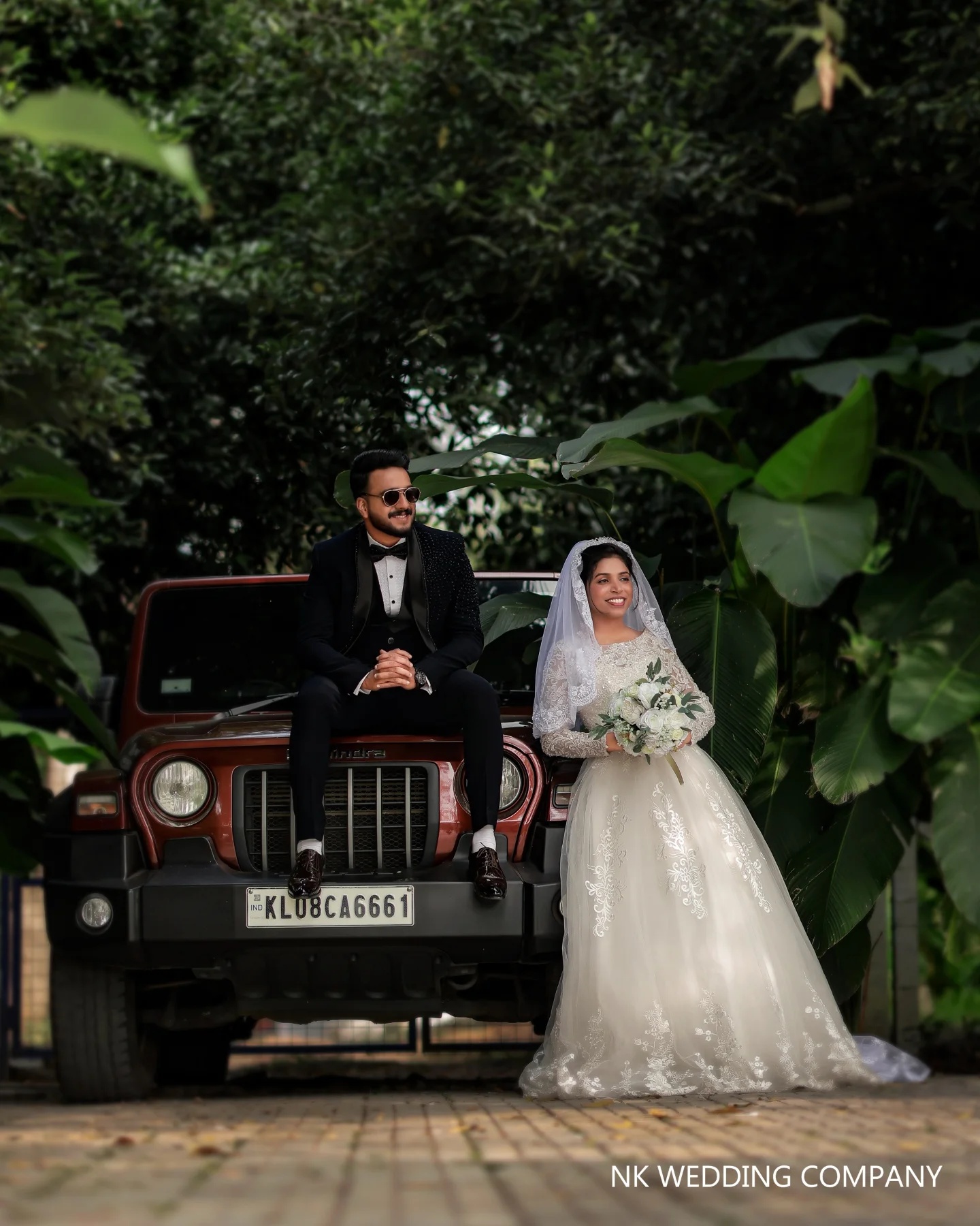 Newlyweds beside a vintage jeep in a tropical setting